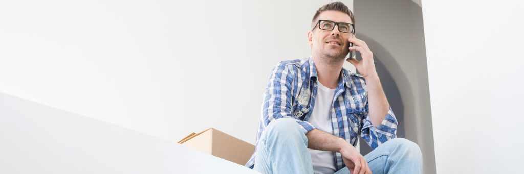 Die Umzugsfirma Zürich Menspower ermöglicht einen stressfreien Umzug, während ein zufriedener Kunde entspannt telefoniert inmitten sorgfältig gepackter Kartons.
