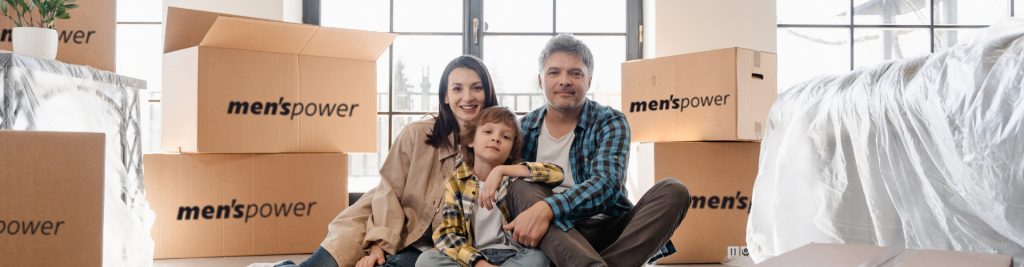 E Familie hockt zfride zwüsche Zügekartone vo Menspower – d Umzugsfirma Zürich für en stressfreie und sichere Züg